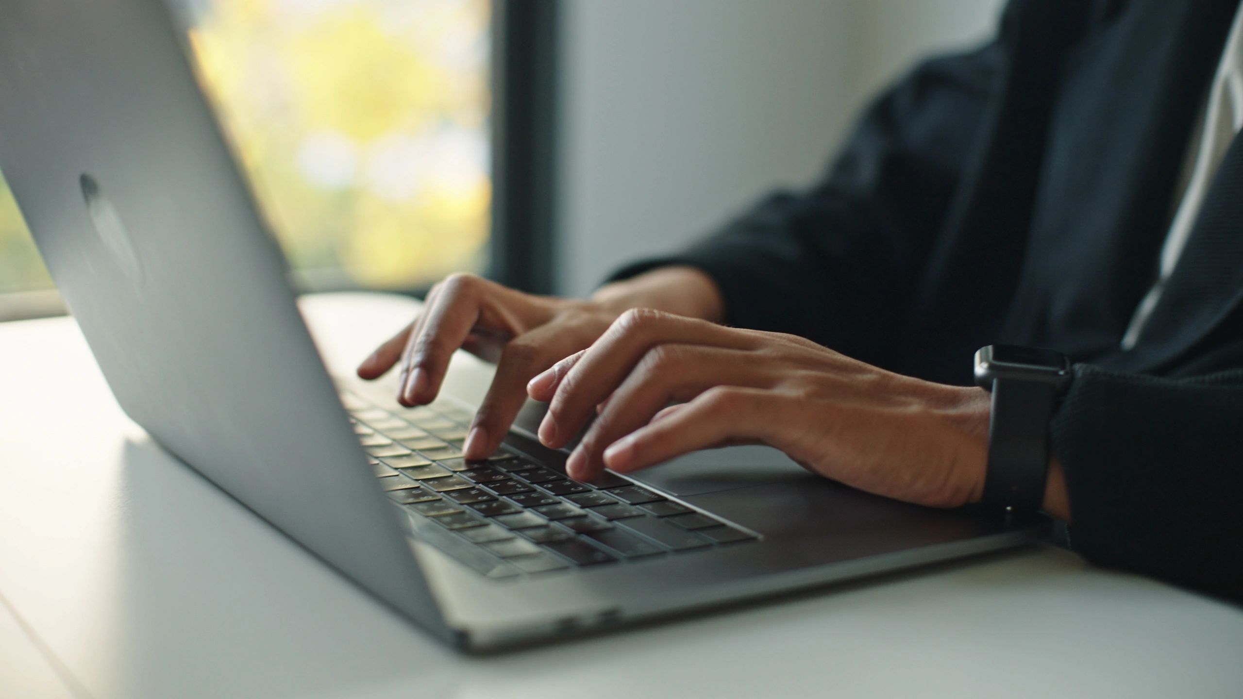 Hands typing on a laptop keyboard
